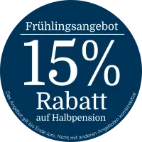 Rundes dunkelblaues Werbebadge mit der Aufschrift „Frühlingsangebot“ auf Deutsch, „15 % Rabatt auf Halbpension“ sowie dem Hinweis, dass das Angebot bis Ende Juni gültig und nicht mit anderen Angeboten kombinierbar ist.