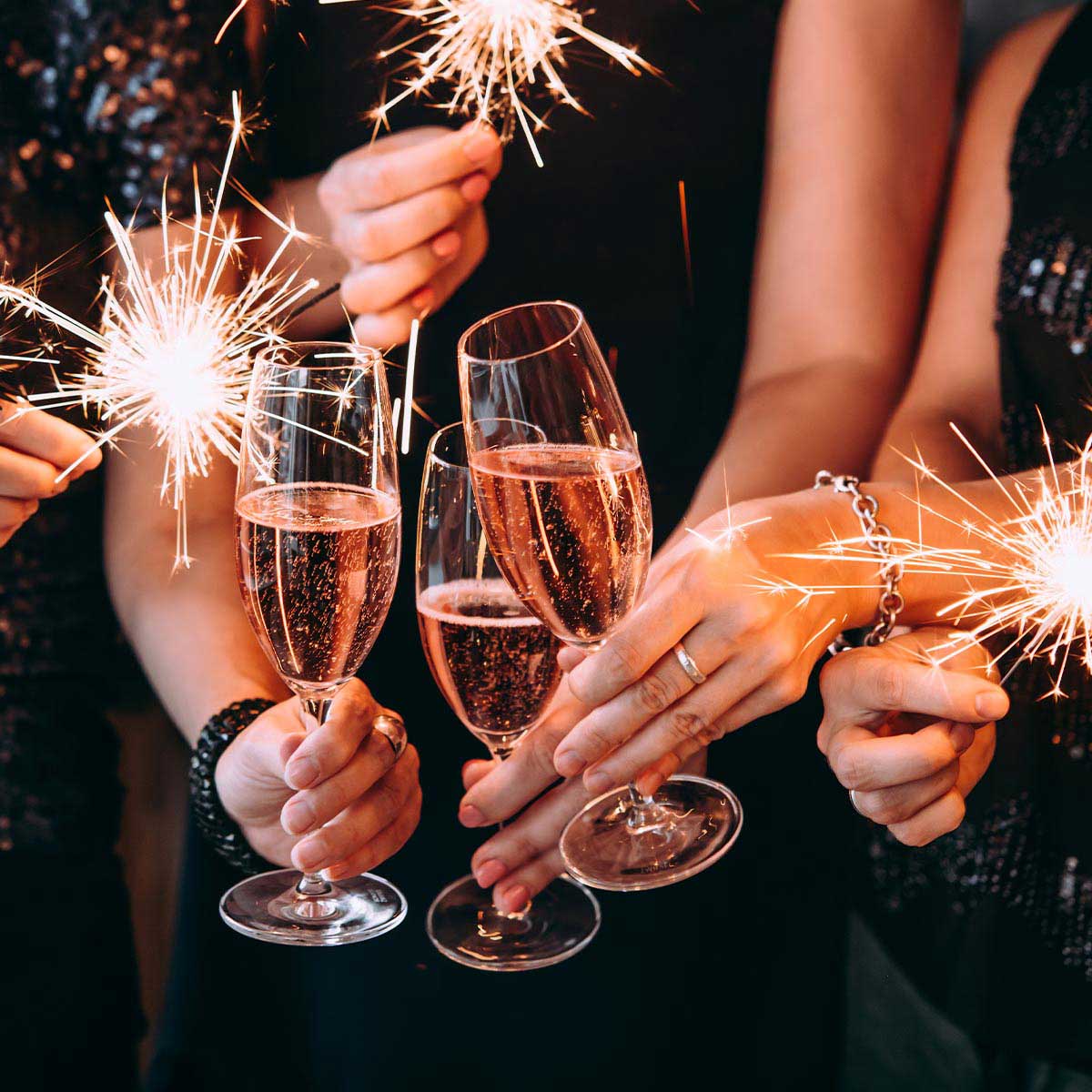 Close-up of people celebrating at the New Year's Eve party at the Grand Hotel Binz with champagne glasses and sparklers in their hands.
