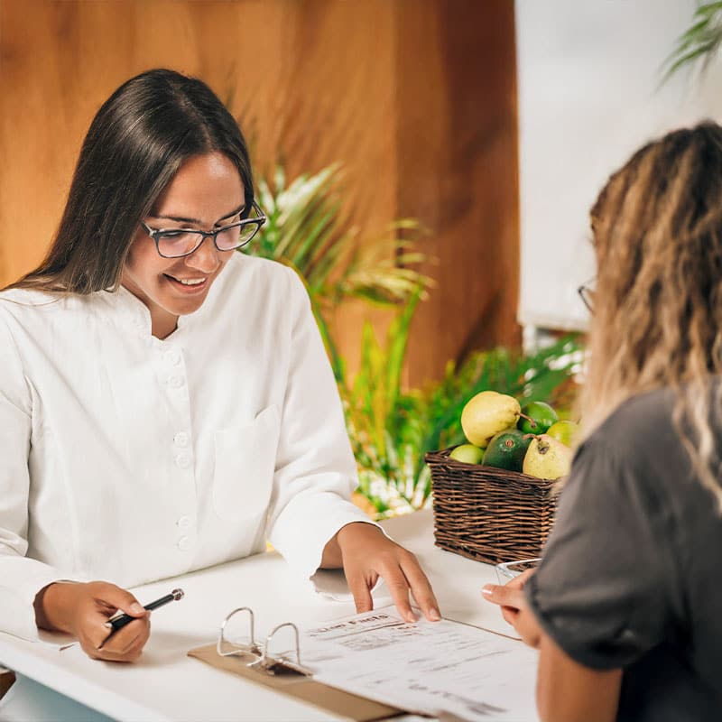 Eine Ayurveda-Ärztin berät ihre Kundin anhand von Unterlagen.