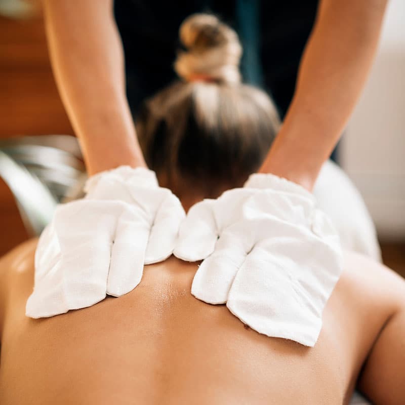 Eine Frau erhält eine Rückenmassage mit original ayurvedischen Seidenhandschuhen.