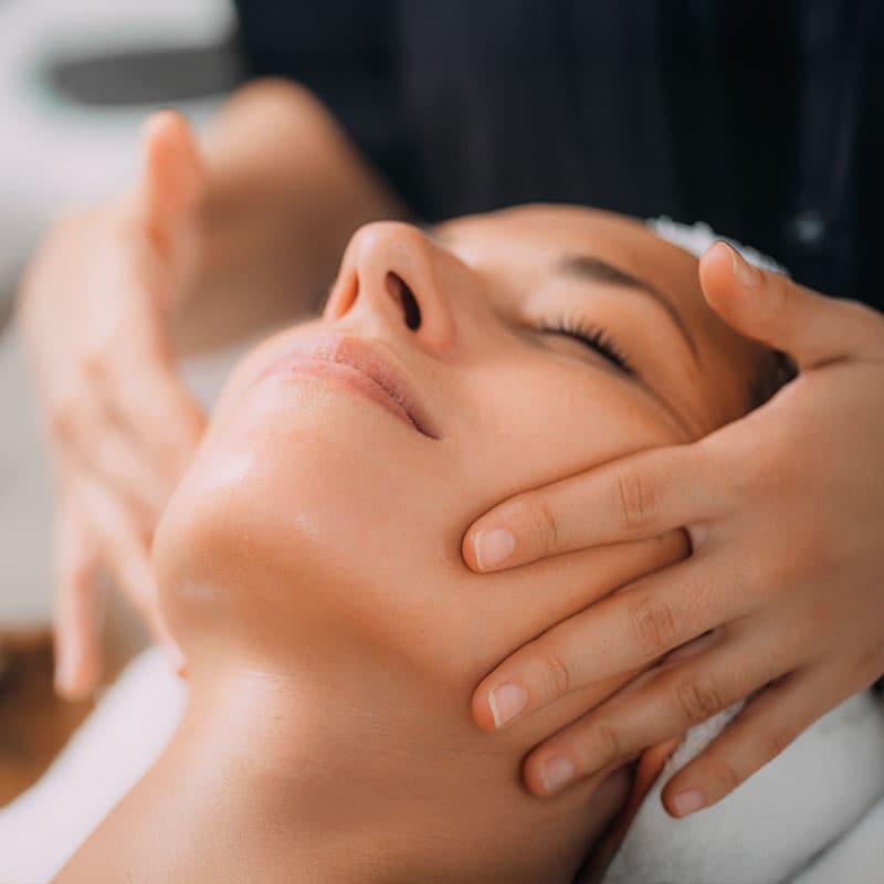 Eine Frau genießt die angenehme Lockerung durch eine Gesichtsmassage.