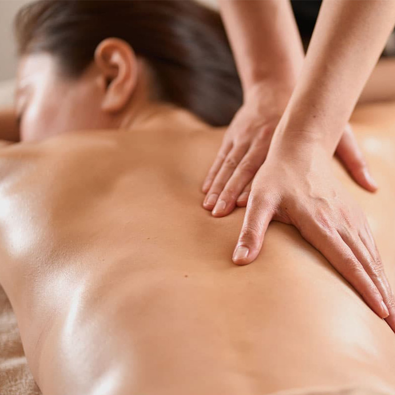 Entspannende Ayurvedamassage mit Heilkräuteröl am Rücken eines Gastes.