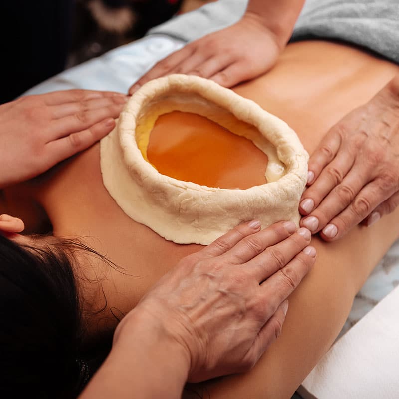 Ayurvedischer Teigring zur Schmerzbehandlung auf einem Rücken.