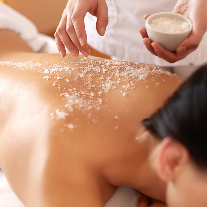 Application of a full body peeling on the back, with fine sea salt and nourishing oil for noticeably soft skin.