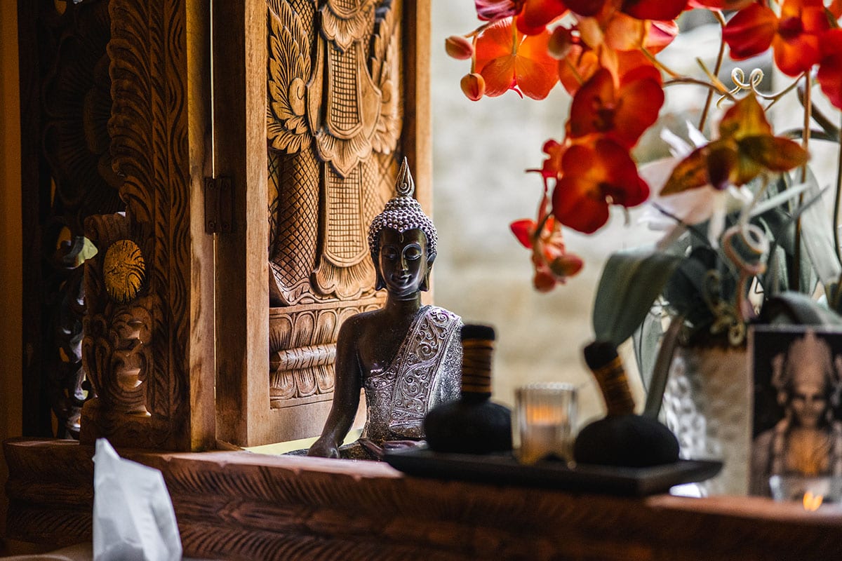 Detailaufnahme von Orchideen und Buddhafigur im Thai-Bali Spa